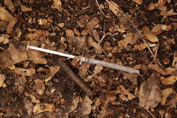 細い注射器中毒者は乾燥した葉の上に横たわっています中毒の概念 — ストック写真