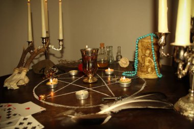 Mumlar yuvarlak bir masanın karanlık bir odasında, gümüş şamdanlarda, falcılık kartları seriliyor, bir pentagram çiziliyor, bir sihir ve büyücülük konsepti.