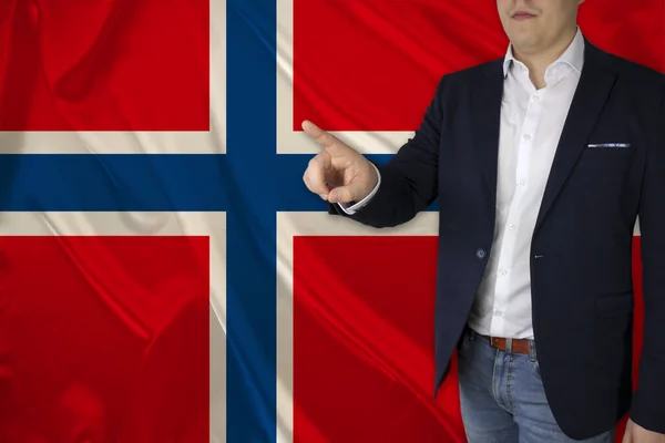 businessman shows his finger on the background of the silk national flag of the modern state of Norway, the concept of tourism, economy, politics, business, globalization