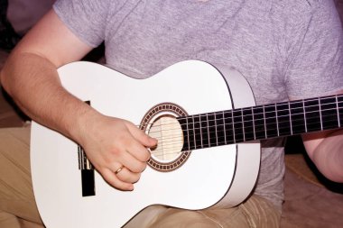 Beyaz altı telli ahşap gitar çalan bir adam, müzikal konsept, yakın plan.
