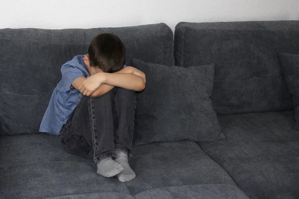 Niño Niño Sentado Sofá Gris Habitación Apretando Las Rodillas Con —  Fotos de Stock