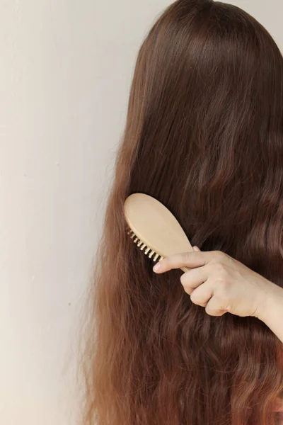 Dívka Dlouhými Hnědýma Vlasy Pročesuje Dřevěným Hřebenem Svislým Blízkým — Stock fotografie