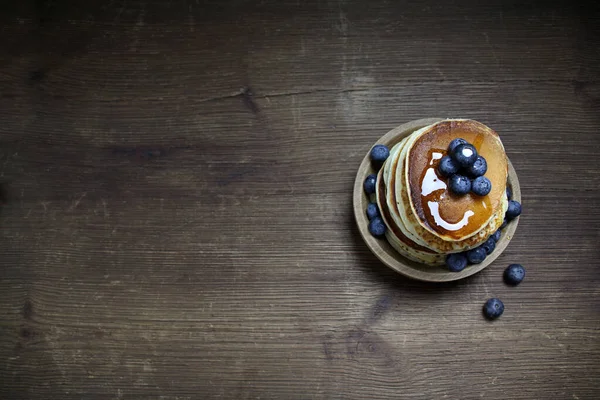 top view of national dish pancakes, pancakes, pita with blueberries, linen napkin, poured with honey, concept of traditional cuisine