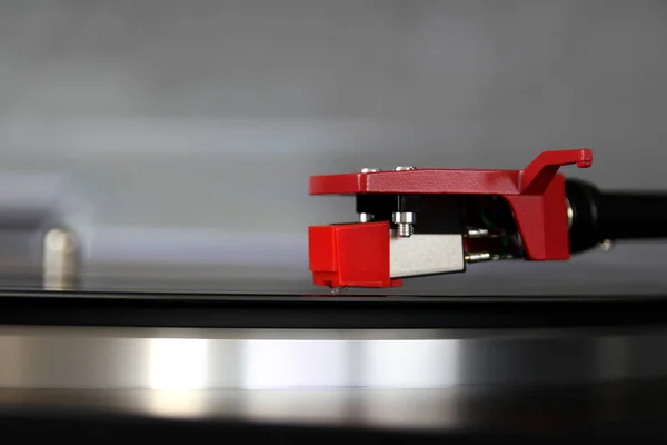 pickup head stands on a blurred black music disc for vinyl player, retro music concept, lifestyle