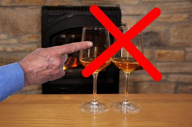 two glasses of wine in front of the fireplace crossed out with a red cross, a male hand shows the concept of giving up alcohol clipart