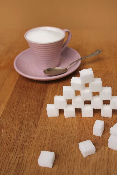 sugar cubes made from sugar cubes, full of pink tea cup and saucer, refined slices, the concept of excess sugar consumption, diabetic, close-up, copy space