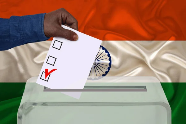 male voter drops a ballot in a transparent ballot box against the background of the india national flag, concept of state elections, referendum