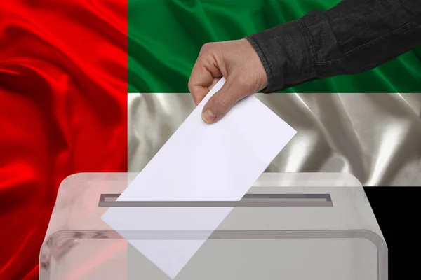 男性の有権者は アラブ首長国連邦の国旗 国家選挙の概念 国民投票を背景に 透明な投票箱に投票を落とします — ストック写真