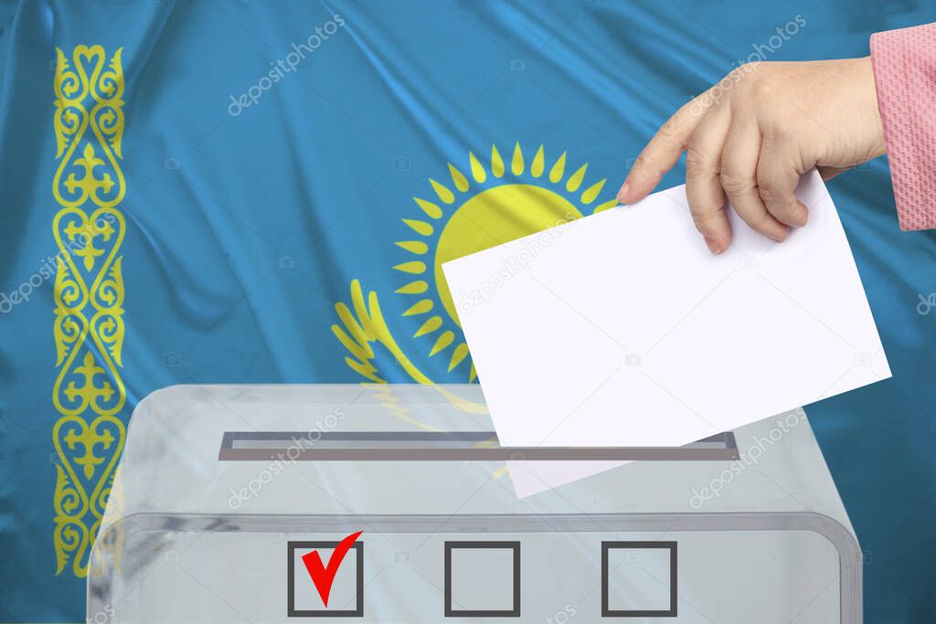 female voter drops a ballot in a transparent ballot box against the background of the national flag of Kazakhstan, concept of state elections, referendum