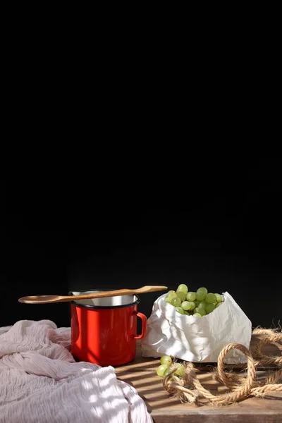 纸袋中的葡萄躺在一张木制桌子上 一只旧勺子和一个红色的瓷瓶 在桌上的光芒中闪烁着 这是一个复古的概念 — 图库照片
