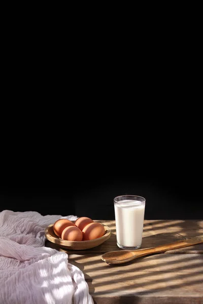 牛奶杯 木制桌子上的褐色鸡蛋 一只旧勺子和一个红色的瓷瓶 在桌上的光芒中闪烁着光芒 这些都是复古的概念 — 图库照片
