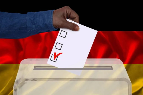 ドイツの国旗 国民投票の概念 国民投票を背景に 男性有権者は透明な投票箱に投票を落とします — ストック写真