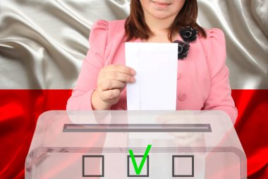 Kadın seçmen, Polonya bayrağı, devlet seçimleri ve referandumun arka planına karşı şeffaf bir oy sandığında oy kullanıyor.