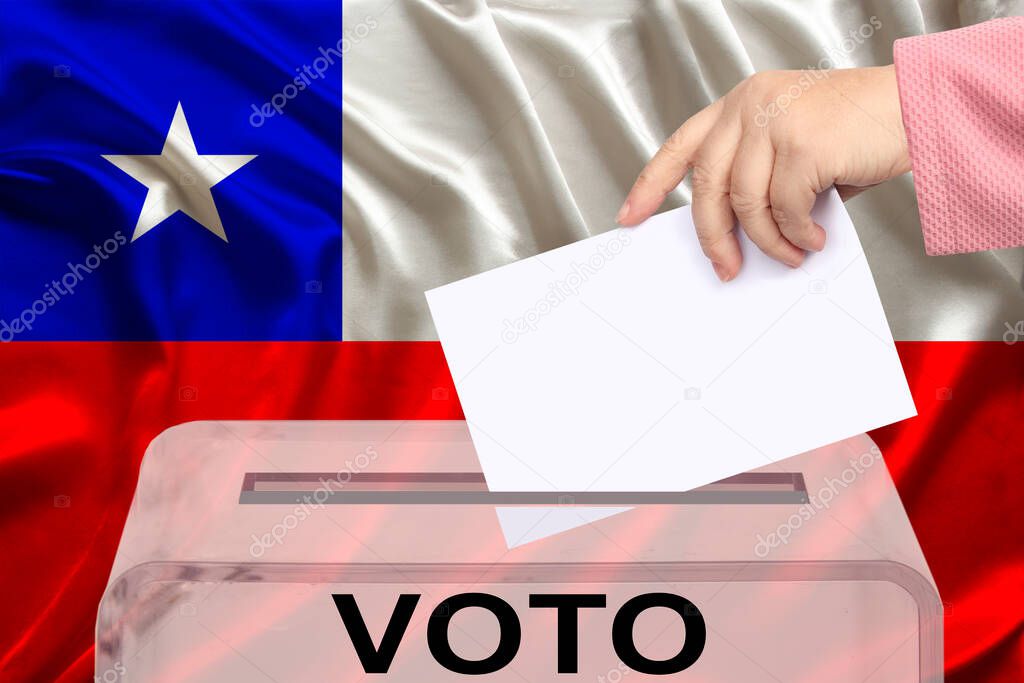 female voter drops a ballot in a transparent ballot box on the background of the national flag of Chile, vote in spanish, concept of state elections, referendum