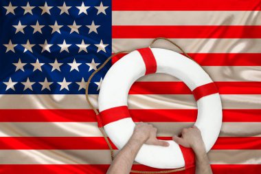Erkek elleri, ABD ülkesinin ipek ulusal bayrağı, sağlık sigortası, turizm, felaket kavramına karşı bir can simidi tutuyor.