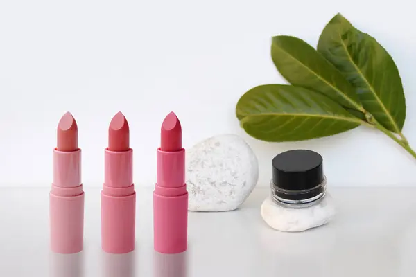 Set Tubes Lipstick Stand White Background Vibrant Green Leaves Lip — Stock Photo, Image