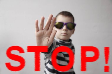 Koyu renk güneş gözlüklü çocuk avucunu kapatıyor, dur hareketi, ele seçici odaklanma, protesto konsepti, 