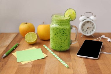 Ahşap bir masada kullanışlı salatalık, kırmızı biber, ıspanak, telefon, çalar saat, elma, kağıt, sağlıklı beslenme konsepti,