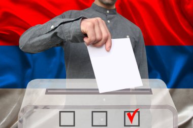 Erkek seçmen, Sırbistan ulusal bayrağı, devlet seçimleri konsepti ve referandumun arka planında şeffaf bir oy sandığına oy attı