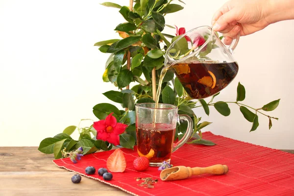 girl holds in her hands a teapot with tea leaves, herbal tea, in the background fruits, dry fruit, berries, flowers, the concept of a healthy diet, diet, vitamin drink, quenching thirst