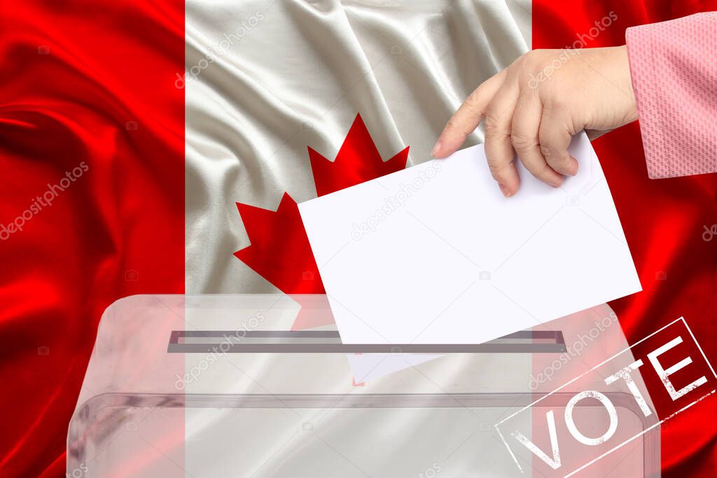 female voter drops a ballot in a transparent ballot box against the background of the national flag of Canada, concept of state elections, referendum