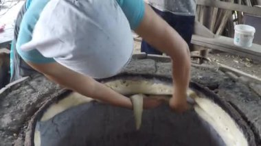 Kadın Gürcistan 'da bir kil dikenli fırında ekmek pişiriyor, Gürcistan' da ulusal hamur işleri hazırlıyor, geleneksel Gürcü mutfağı kavramı, ev işi, kadın işi