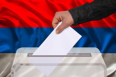 Erkek seçmen, Sırbistan ulusal bayrağı, devlet seçimleri konsepti ve referandumun arka planında şeffaf bir oy sandığına oy attı