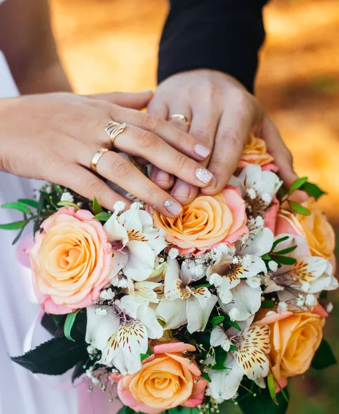 Close-up Las manos de la novia y el novio con anillos de boda y ramo. Amor y matrimonio. Accesorios de boda y decoración — Foto de Stock