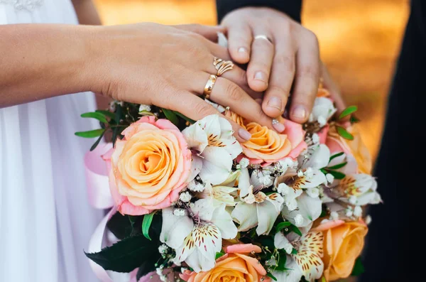 Detail nevěsta a ženich se ruce snubní prsteny a kytice. Láska a manželství. Svatební doplňky a výzdoba — Stock fotografie