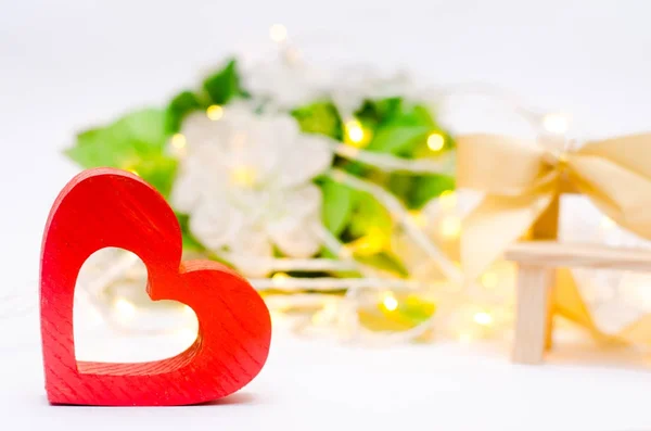 Houten hart met een boog op een bankje op een witte achtergrond. Aftelkalender voor Valentijnsdag — Stockfoto