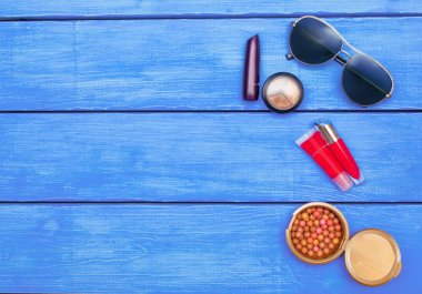 Mavi ahşap arka plan, gözlük makyaj ürünleri. metin için yer