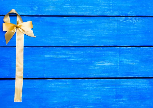 Yellow ribbon on a blue wooden background, yellow  bow — Stock Photo, Image