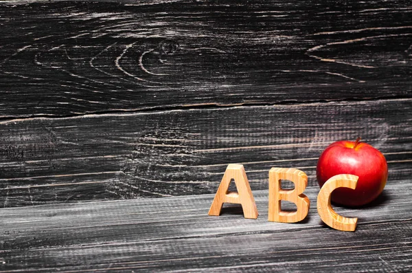 Letras do alfabeto e maçã vermelha em um fundo preto . — Fotografia de Stock