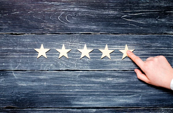 Die Hand einer Frau zeigt auf den fünften Stern. Der Qualitätsstatus beträgt fünf Sterne. ein neuer Stern, Leistung, universelle Anerkennung. — Stockfoto