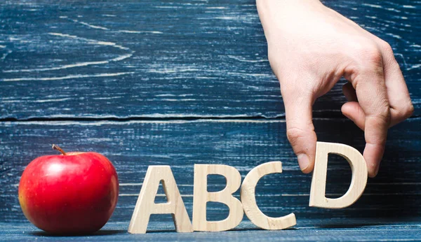 Maçã vermelha e letras ABCD. A mão coloca a letra D — Fotografia de Stock