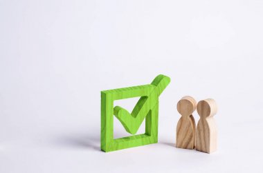 İki ahşap insan figürleri birlikte yeşil bir onay kutusunun yanındaki bekletin. Seçimler ve sosyal teknolojileri kavramı. Gönüllüler, partiler, adaylar, seçim electorates. İnsan hakları.