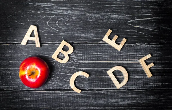 Mela rossa e alfabeto fatto di lettere di legno su uno sfondo scuro di un consiglio scolastico. Mela per l'insegnante. Il concetto di scuola elementare, college, università, istruzione. Istruzione, istruzione . — Foto Stock