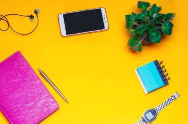 bir defter, kalem, saat, telefon, sarı bir arka plan üzerinde kulaklık ile çalışma alanı. metin için yer. Çalışma alanı bir serbest meslek sahibi, gazeteci, yazar. Parlak sarı bir arka plan üzerinde. Üstten Görünüm.
