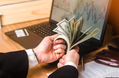 Takım elbiseli bir adam ekonomik grafikler ile bir laptop para sayar. Gayrimenkul yatırımları. İş fikirleri, başarı öyküsü. İkili Müzayede Mali piramit. Ekonomik patlama kavramı.