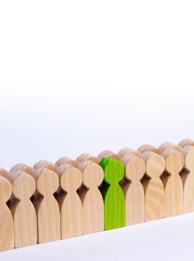 Seçilmiş kişi diğerleri arasında. Yeşil renk bir insan figürü kalabalığın içinde duruyor. Ahşap figürler insan. Yetenekli bir işçi, başarılı bir seçim. Promosyon. Bir çalışan için arama kavramı.