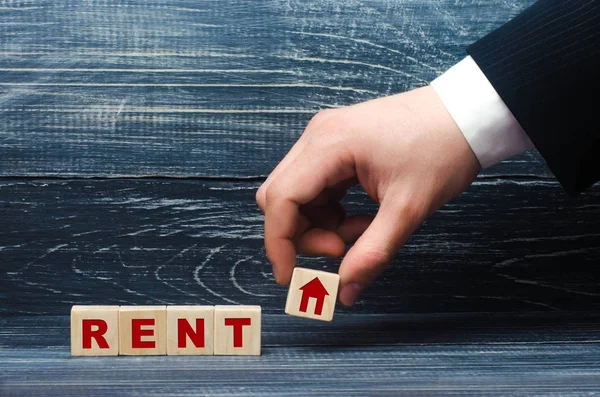 La mano sostiene un cubo con un símbolo de la casa para la palabra arrendamiento. Alquiler y alquiler de una casa en alquiler, apartamento y búsqueda de bienes raíces. Casa propia o vivienda de alquiler . — Foto de Stock