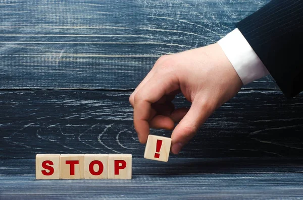 La mano sostiene un cubo con el símbolo del signo de exclamación de la palabra stop. El concepto de advertencia, exige parar, dejar de actuar. Terminación, cancelación, prohibición y tabú . —  Fotos de Stock