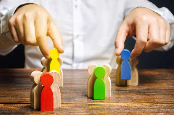 Groups of multicolored wooden people and businessman. The concept of market segmentation. Target audience, customer care. Market group of buyers. Customer relationship management. Selective focus — Stock Photo, Image