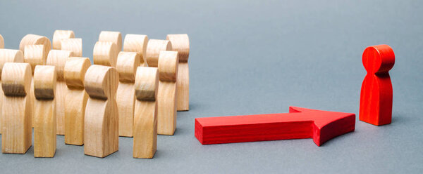 Wooden figures of people. The boss of the business team indicates the direction of movement to the goal. The crowd is following the leader. The concept of leadership and team management