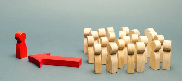 Figure di legno di persone. Il capo del team di lavoro indica la direzione del movimento verso l'obiettivo. La folla sta seguendo il leader. Il concetto di leadership e gestione del team — Foto Stock