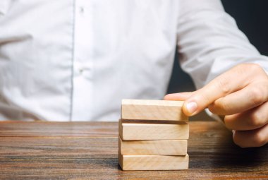 İşadamı tahta bloklar koyar. İş yönetimi konsepti. Planlama ve strateji. Ayarlama ve hedeflere ulaşma. İş dengesi. Yol haritası.