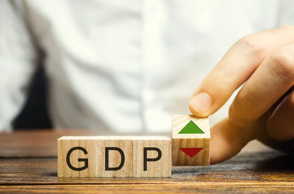 Ξύλινα μπλοκ με τη λέξη Gdp και πάνω και κάτω βέλη. Μια ασταθής οικονομία στη χώρα. Χρηματοοικονομικό μέτρο της αγοραίας αξίας όλων των τελικών αγαθών και υπηρεσιών που παράγονται σε συγκεκριμένη περίοδο. — Φωτογραφία Αρχείου