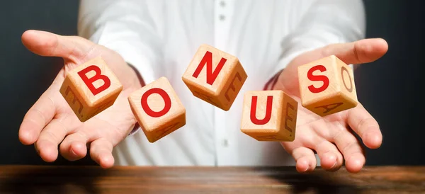 Cubes thrown by a man make up the word BONUS. Receive bonuses, rewards and preferences. Salary increase, wage premium for holidays. Getting benefits and extra points. Promotional gift. rising — Stock Photo, Image