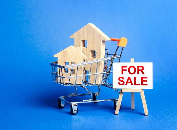 Houses in a shopping cart and an easel sign labeled for sale. Buying and selling real estate, hot offers and property valuation. Smart investments. Discounts and great offers, cheap loans for purchase — Stockfoto