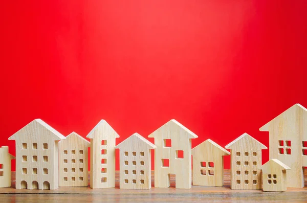 Μικροσκοπικά ξύλινα σπίτια σε κόκκινο φόντο. Σχέδιο ακίνητης περιουσίας. Στην πόλη. Συγκέντρωση και αστικοποίηση. Αναλυτές αγορών. Ζήτηση κατοικίας. Αύξηση και πτώση των τιμών των σπιτιών. Πληθυσμός. Αντιγραφή χώρου — Φωτογραφία Αρχείου